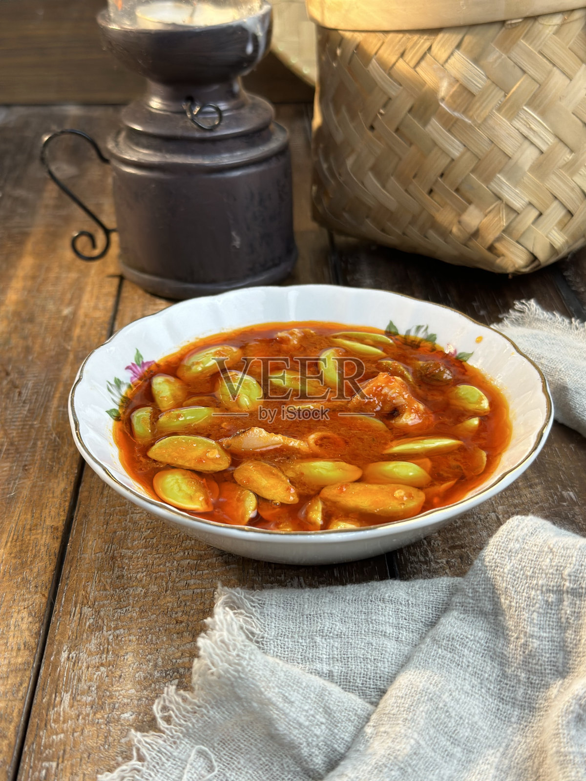 马来西亚菜鱿鱼与臭豆在热辣椒酱或当地被称为sambal petai sotong在白色碗木制背景照片摄影图片