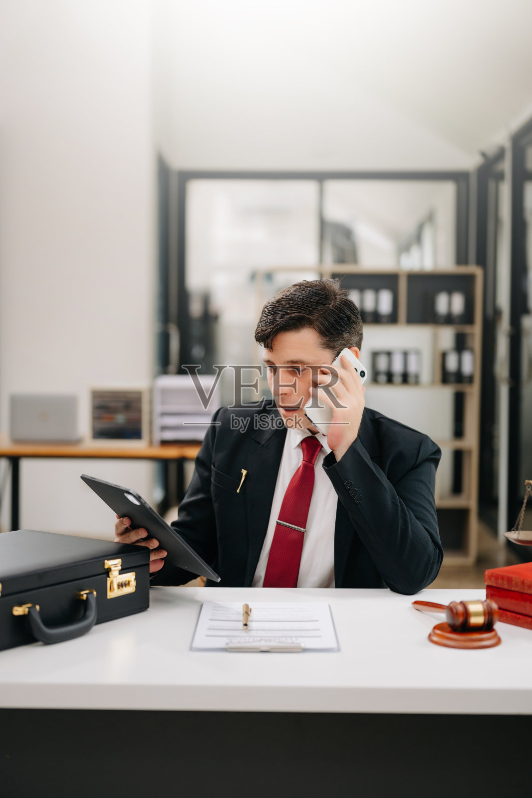 中年男律师在办公室工作,身前有法槌、平板电脑和笔记本电脑,提供法律咨询照片摄影图片