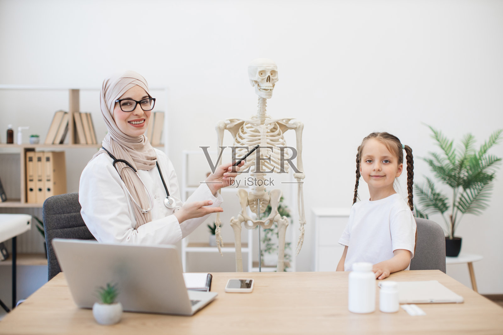 医生和十几岁的女孩在诊所解剖模型附近摆姿势照片摄影图片