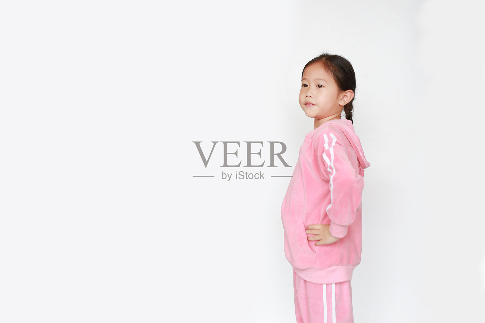 可爱的亚洲小女孩穿着粉红色的运动服或运动服在白色的背景上做运动。照片摄影图片