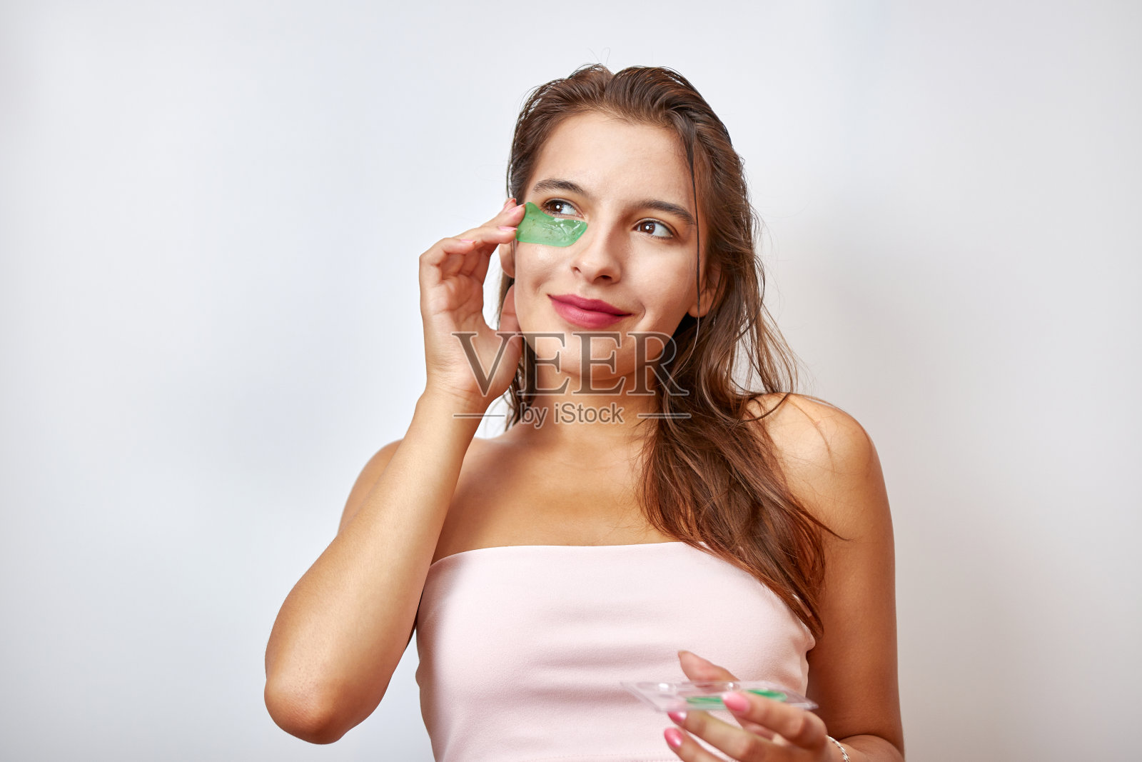 这个女孩在眼睛下面使用胶原蛋白水凝胶贴片。美容理念,化妆品用于眼部周围皮肤的护理,提亮。美容院。皱纹去除。照片摄影图片