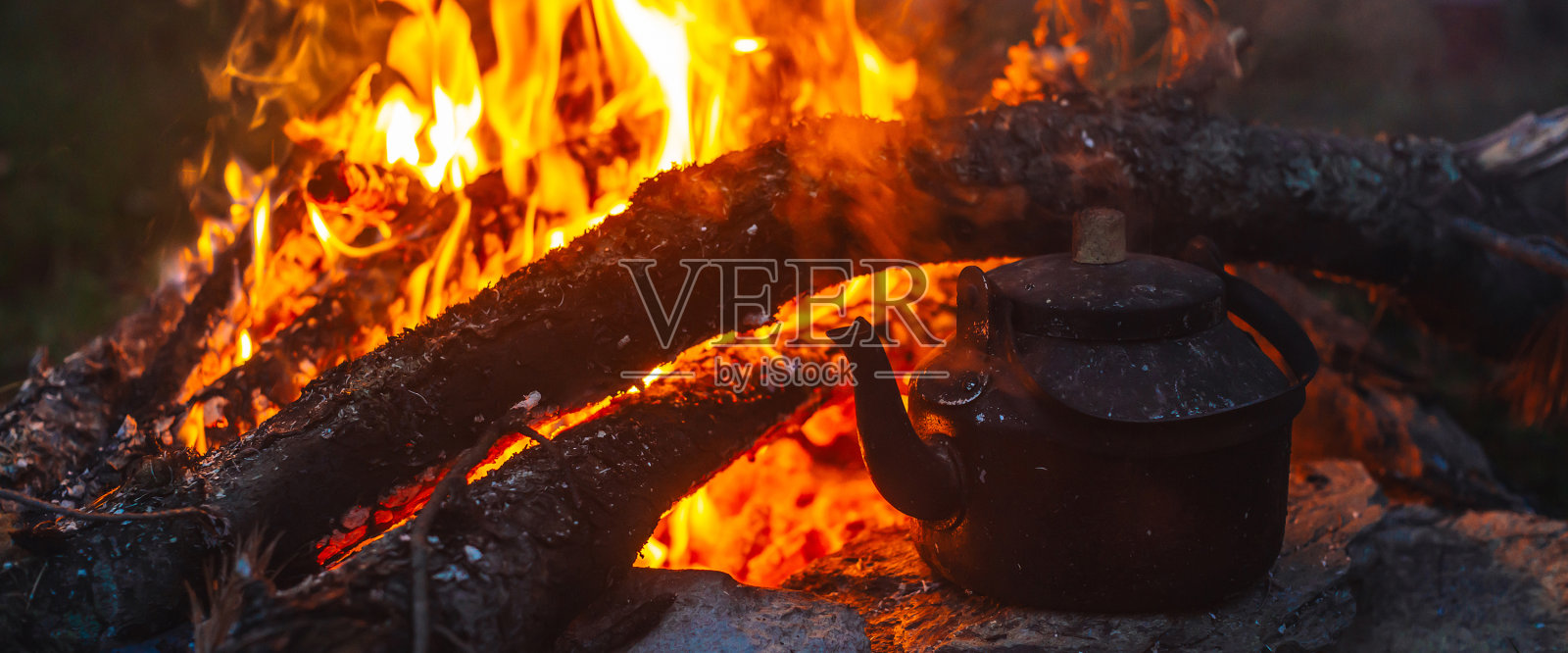 在篝火上用大柴火在水壶里煮茶。在露天喝茶。积极的户外娱乐活动。黄昏露营。浪漫温馨的暮色笼罩着大自然。积极的休息。照片摄影图片