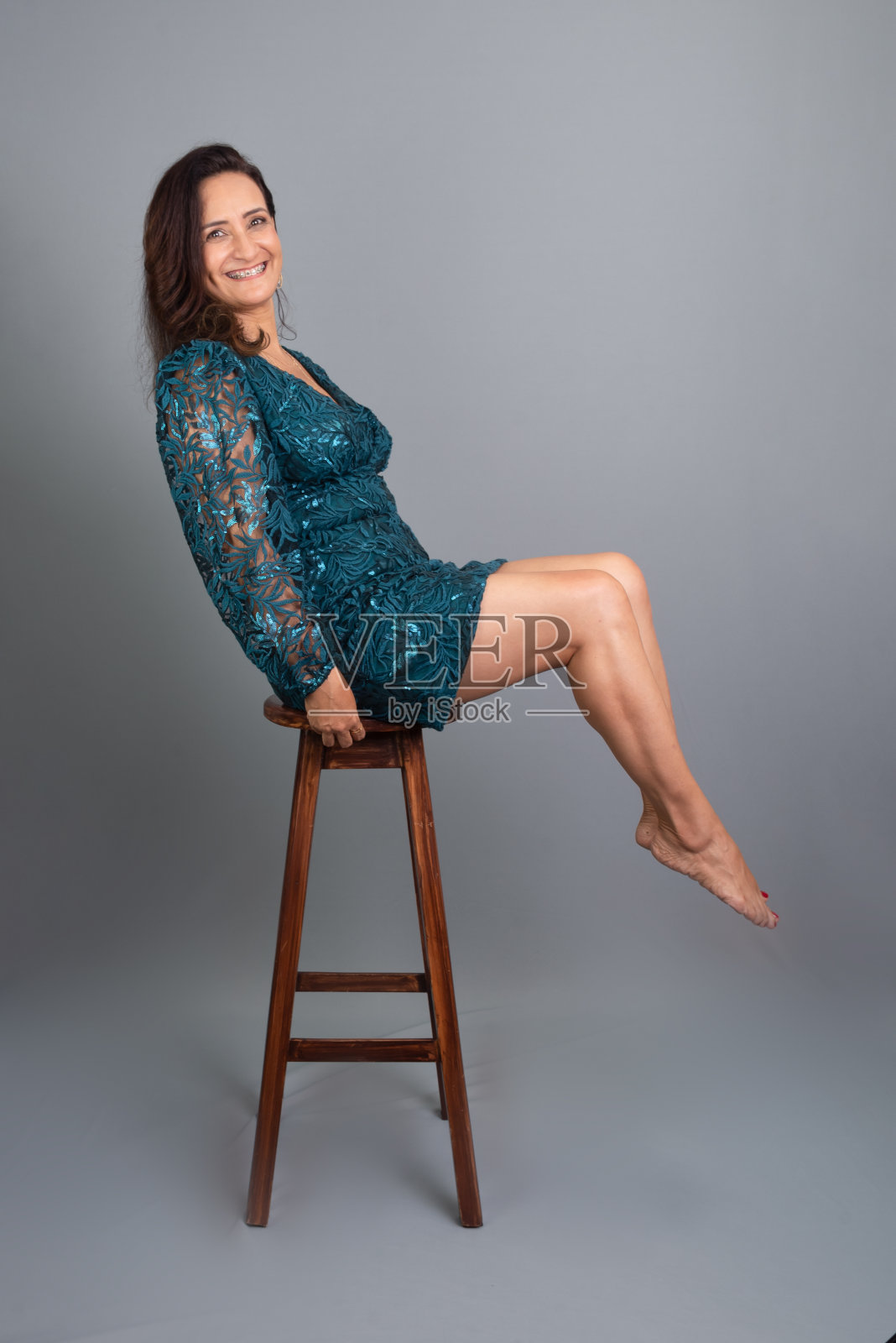 画室里一个美丽成熟的女人坐在木凳上看着镜头。开朗快乐的人。照片摄影图片