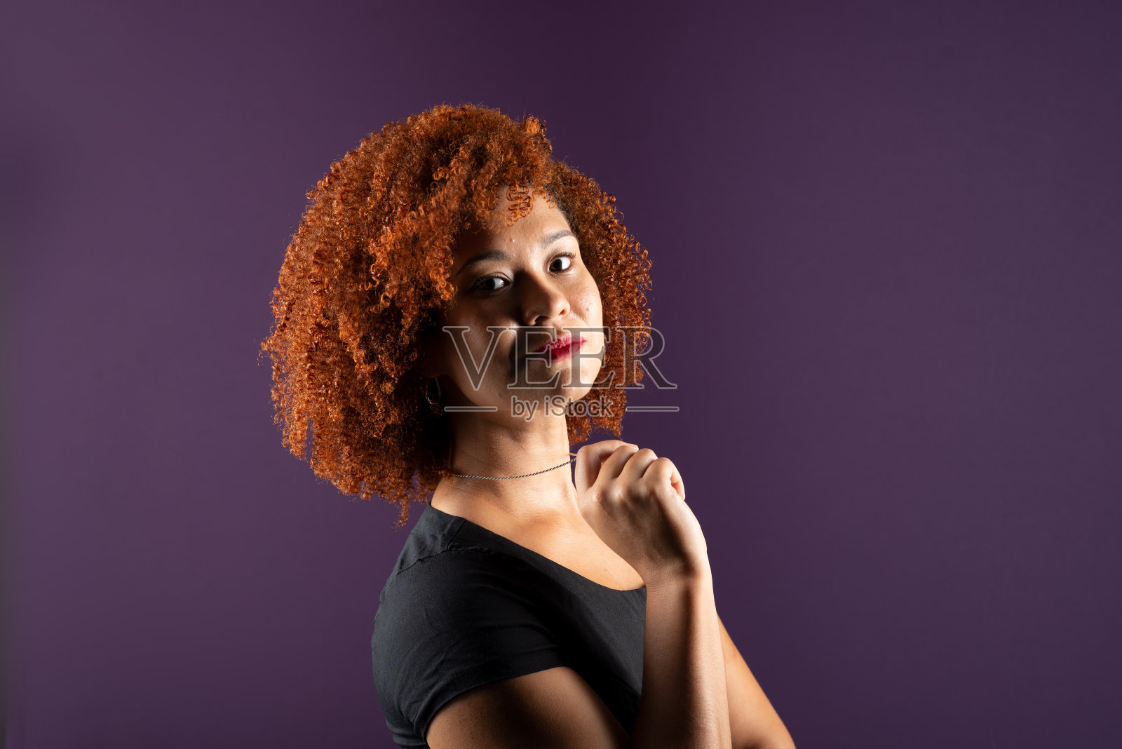 一个迷人的红发女人穿着黑色衣服摆姿势拍照。自信和快乐。照片摄影图片