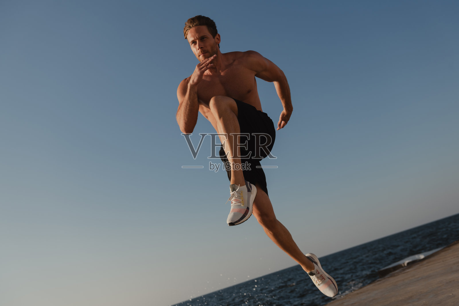 自信的肌肉男以大海为背景跳向户外照片摄影图片