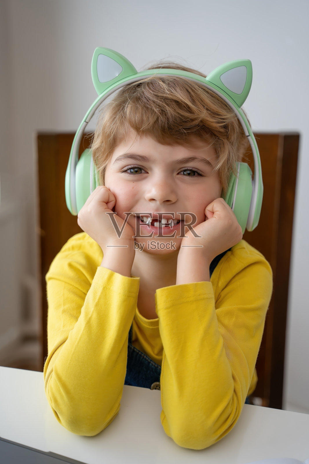 小学生戴着耳机,通过笔记本电脑与老师进行视频通话照片摄影图片