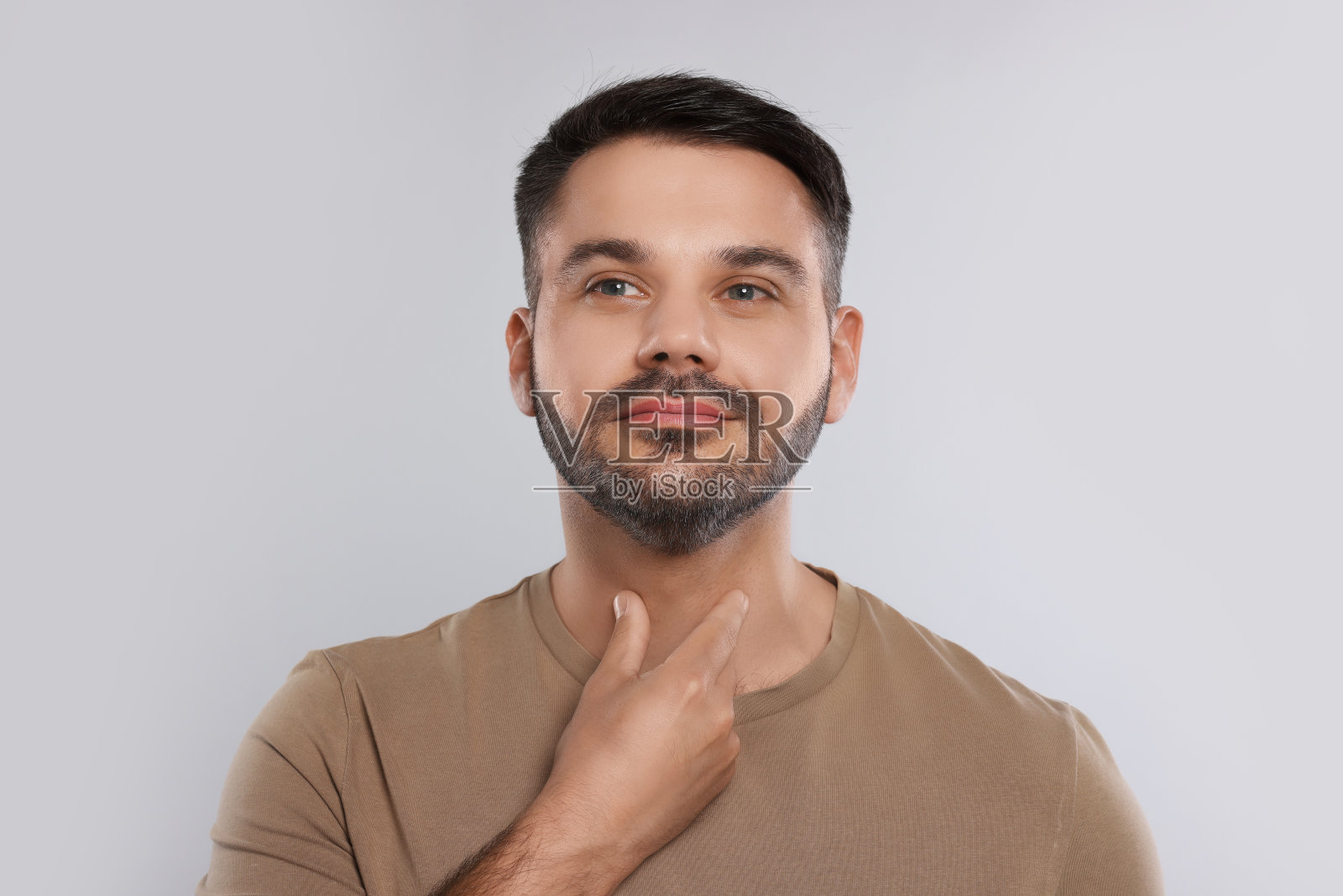 内分泌系统。在浅灰色背景上做甲状腺自我检查的男子照片摄影图片