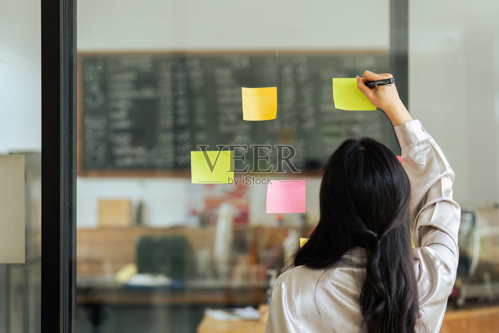 通过女商人的玻璃视图分析流程进度,在粘纸上规划任务照片摄影图片