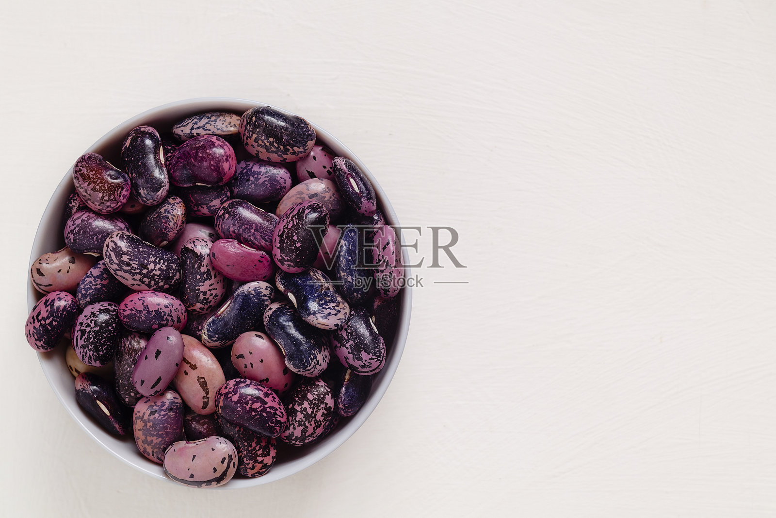 新鲜的紫色、蓝色、猩红的跑腿豆,放在白色的碗里,白色的背景。前视图。副本的空间。照片摄影图片