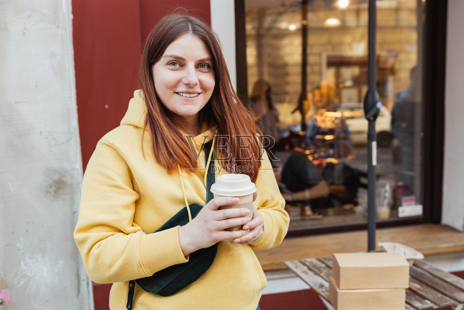 年轻时尚潮人红发女人走在街上,穿着时髦的衣服和喝热拿铁。城市生活方式的旗帜。旅行者。带走送货理念。生态回收,环境友好。照片摄影图片