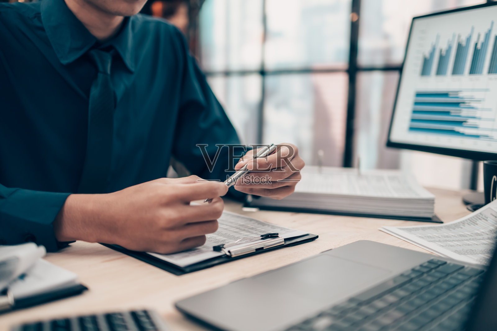 投资者在办公桌办公室工作时拿着笔,在笔记本电脑上检查跟踪成本、余额、项目和货币。会计与财务概念。照片摄影图片