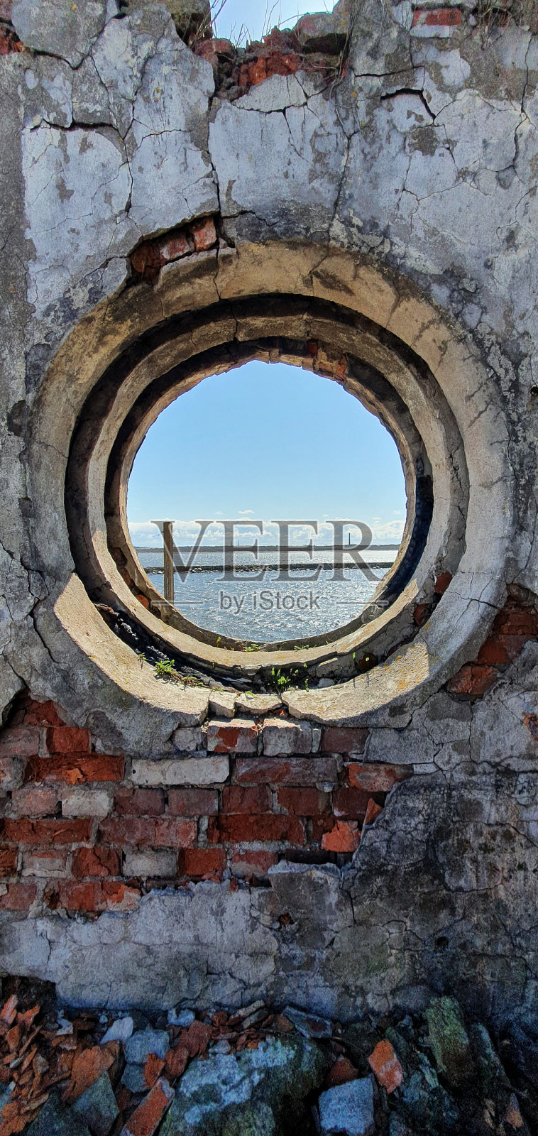 从一幢废弃的老建筑的破碎窗户看到的大海。照片摄影图片