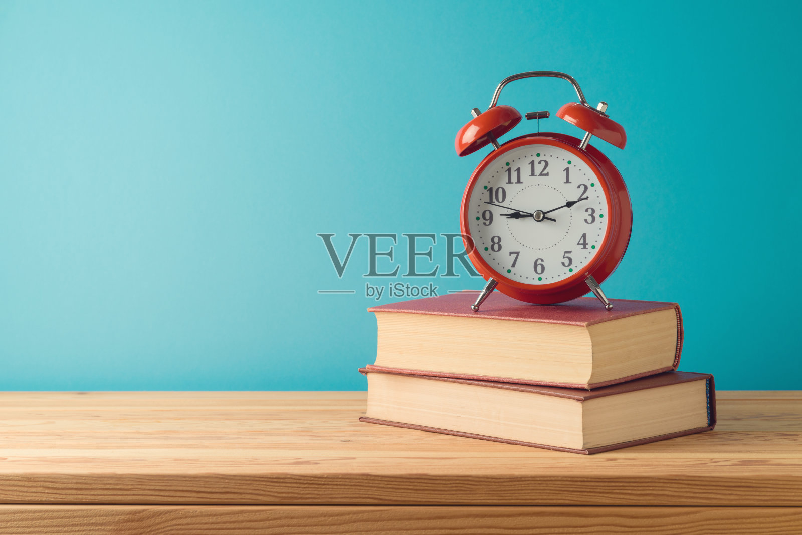 回到学校背景,蓝色背景的木桌上放着书和闹钟照片摄影图片
