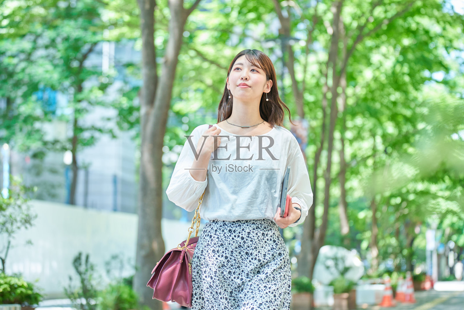 一个女人走在绿色的街道上照片摄影图片