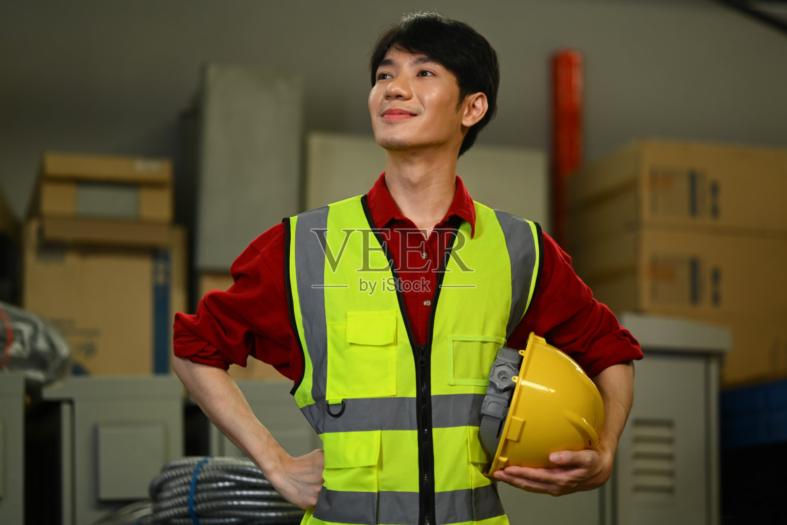 穿着安全背心的帅气仓库工人站在一堆纸板箱旁边照片摄影图片