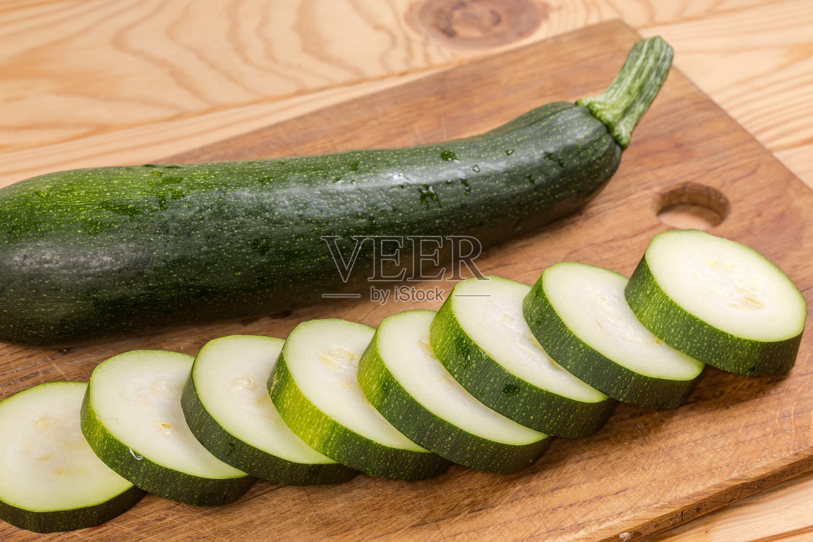 将整个和切片的深绿色西葫芦放在砧板上照片摄影图片