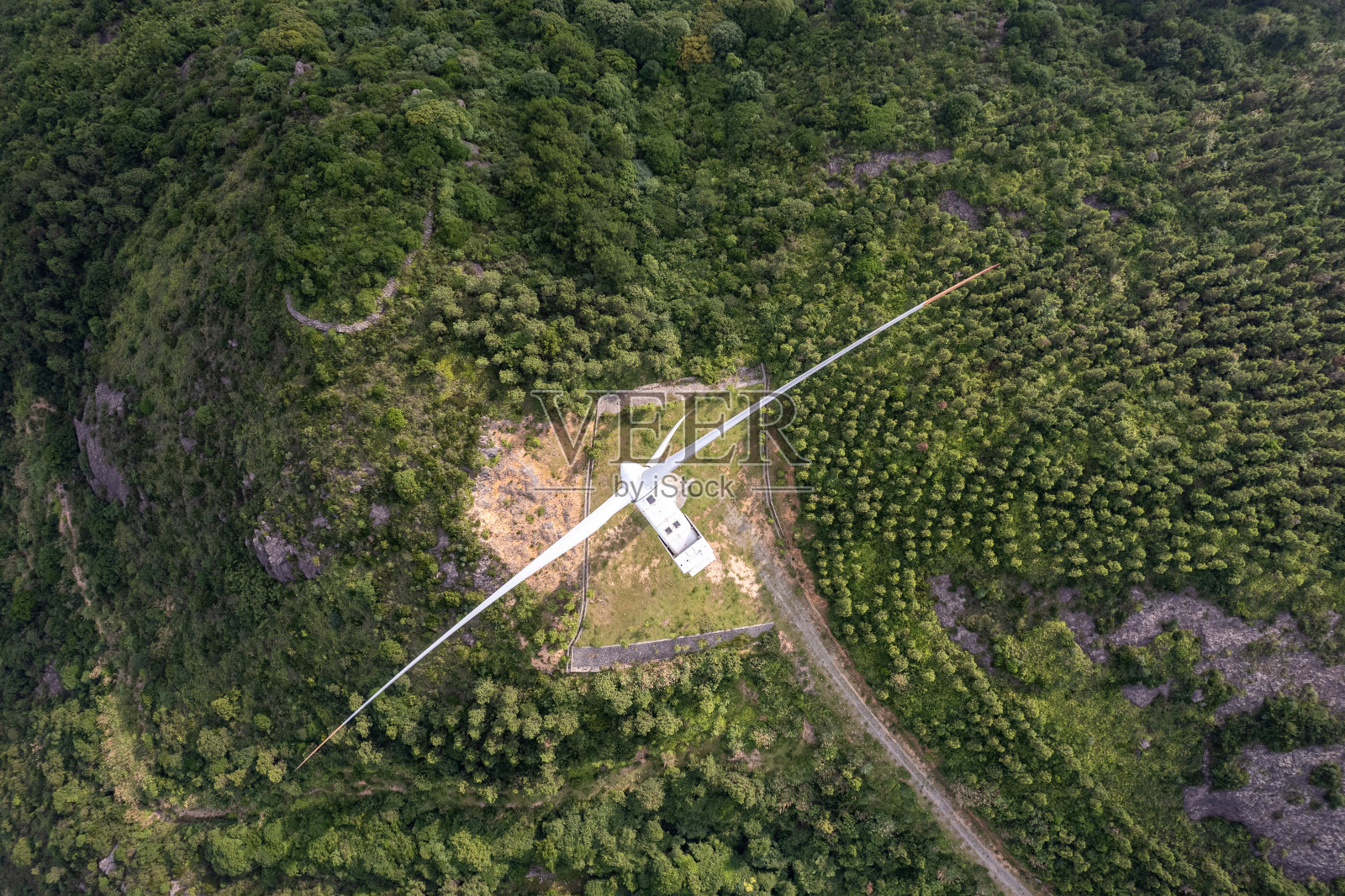 阳光明媚的一天,森林里风力涡轮机的垂直鸟瞰图照片摄影图片