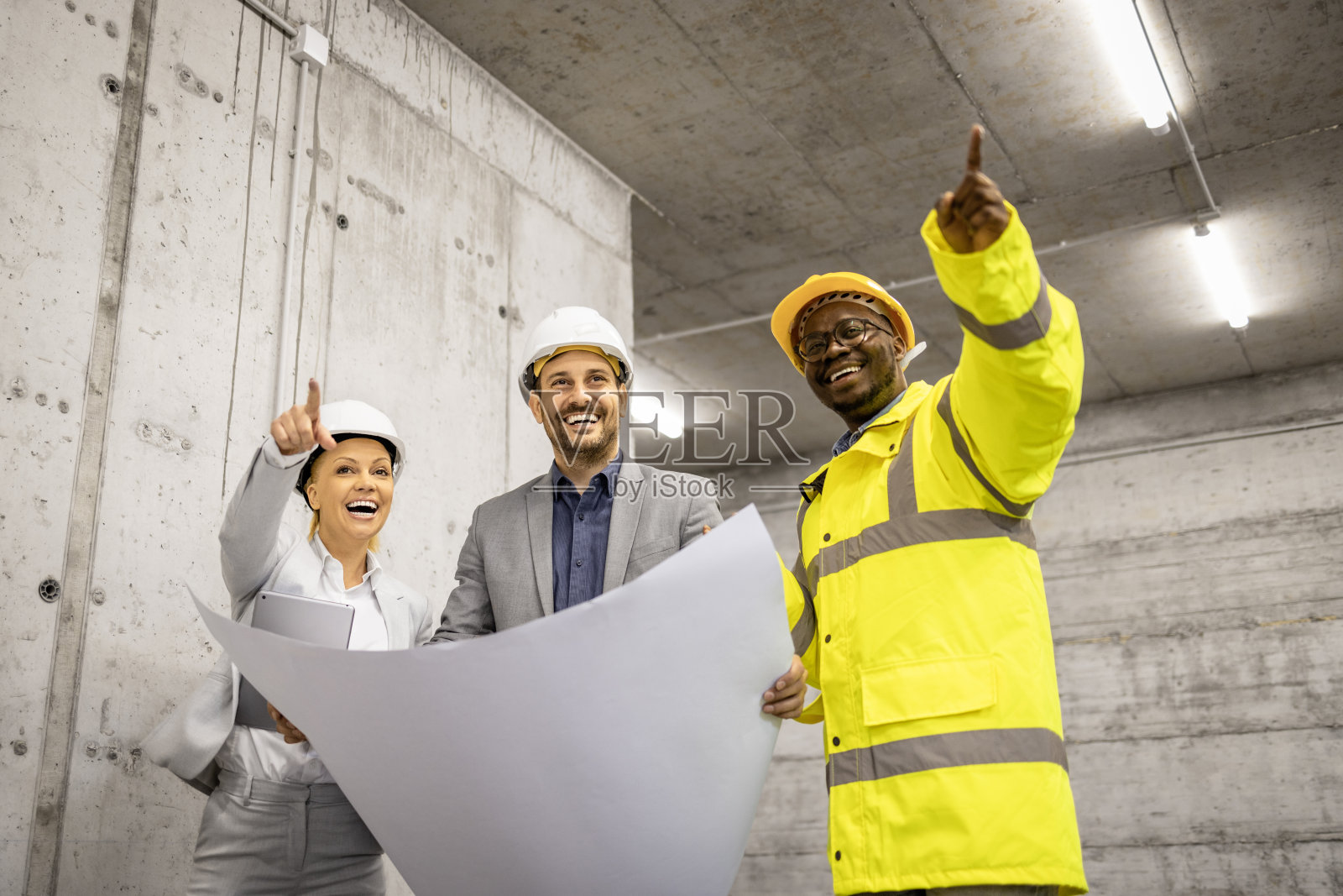 建筑工人和建筑师分析蓝图,一起为新的建筑项目工作。照片摄影图片