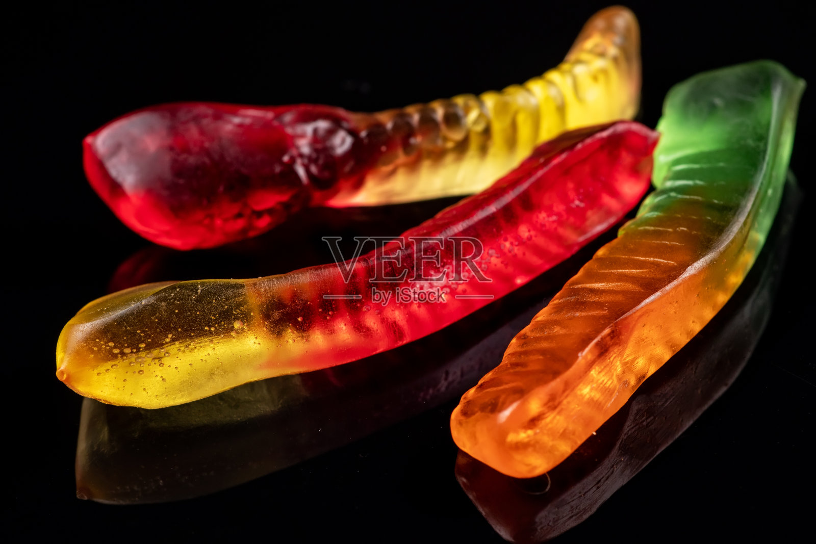 多汁多彩的果冻蠕虫糖果。粘性糖果。蛇。在黑色backgriund照片摄影图片