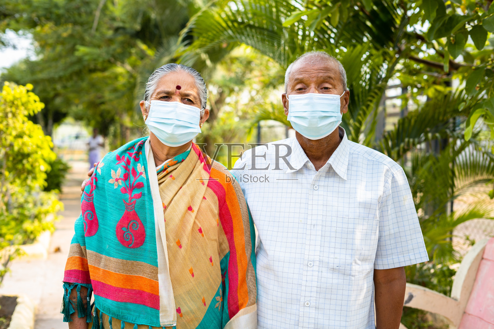 带医用口罩的老年夫妇晨走公园——新冠肺炎防护、医疗保健和安全的概念。照片摄影图片