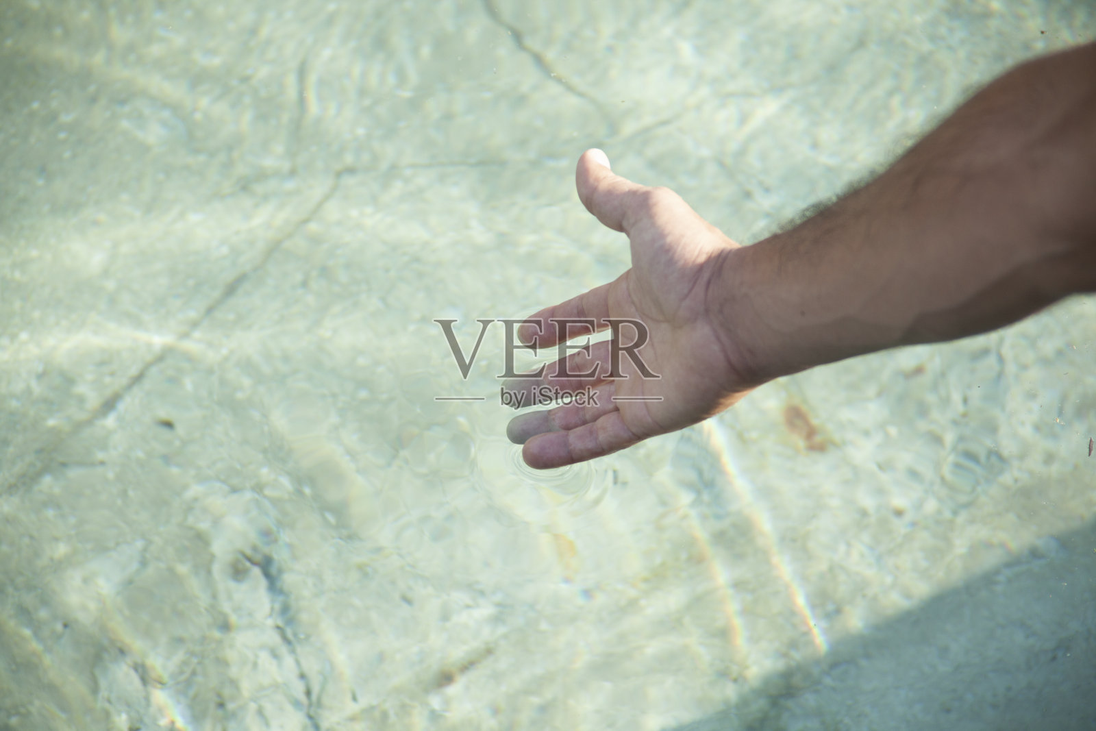 年轻人手伸在池水里照片摄影图片