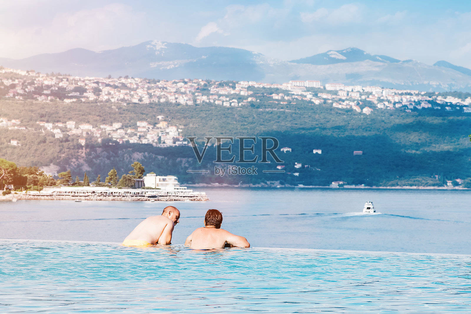 夏季度假时光:男人们在泳池边眺望蓝色大海照片摄影图片