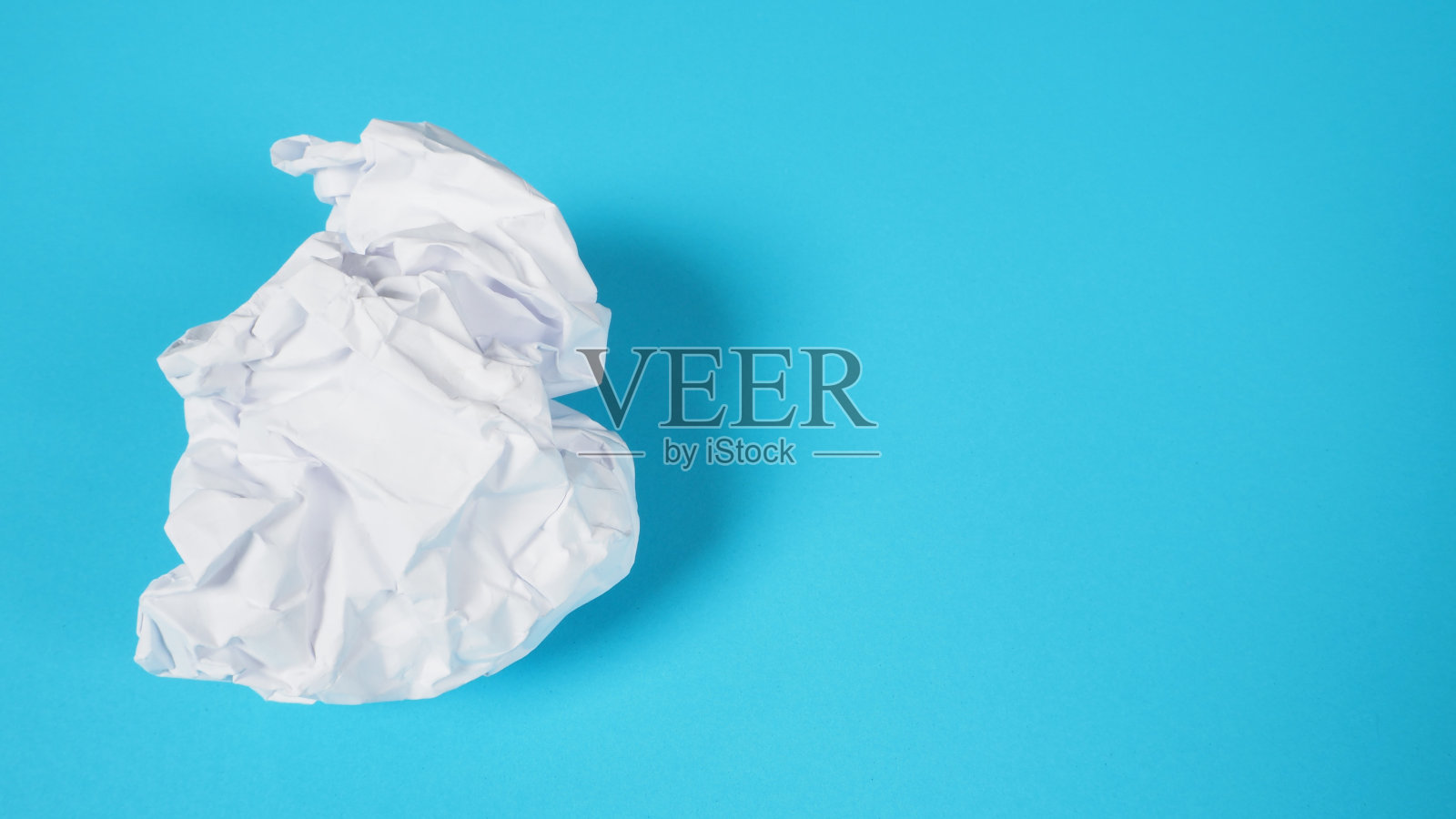 皱巴巴的白纸。它的背景是天蓝色的。照片摄影图片