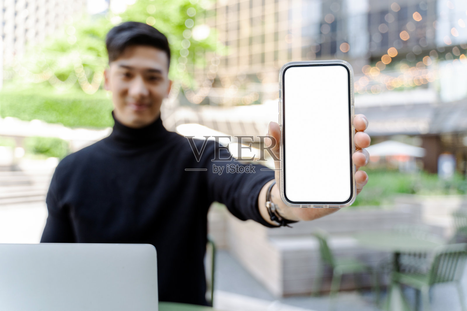 一个亚洲人拿着手机,展示着数字屏幕和模型。技术概念照片摄影图片