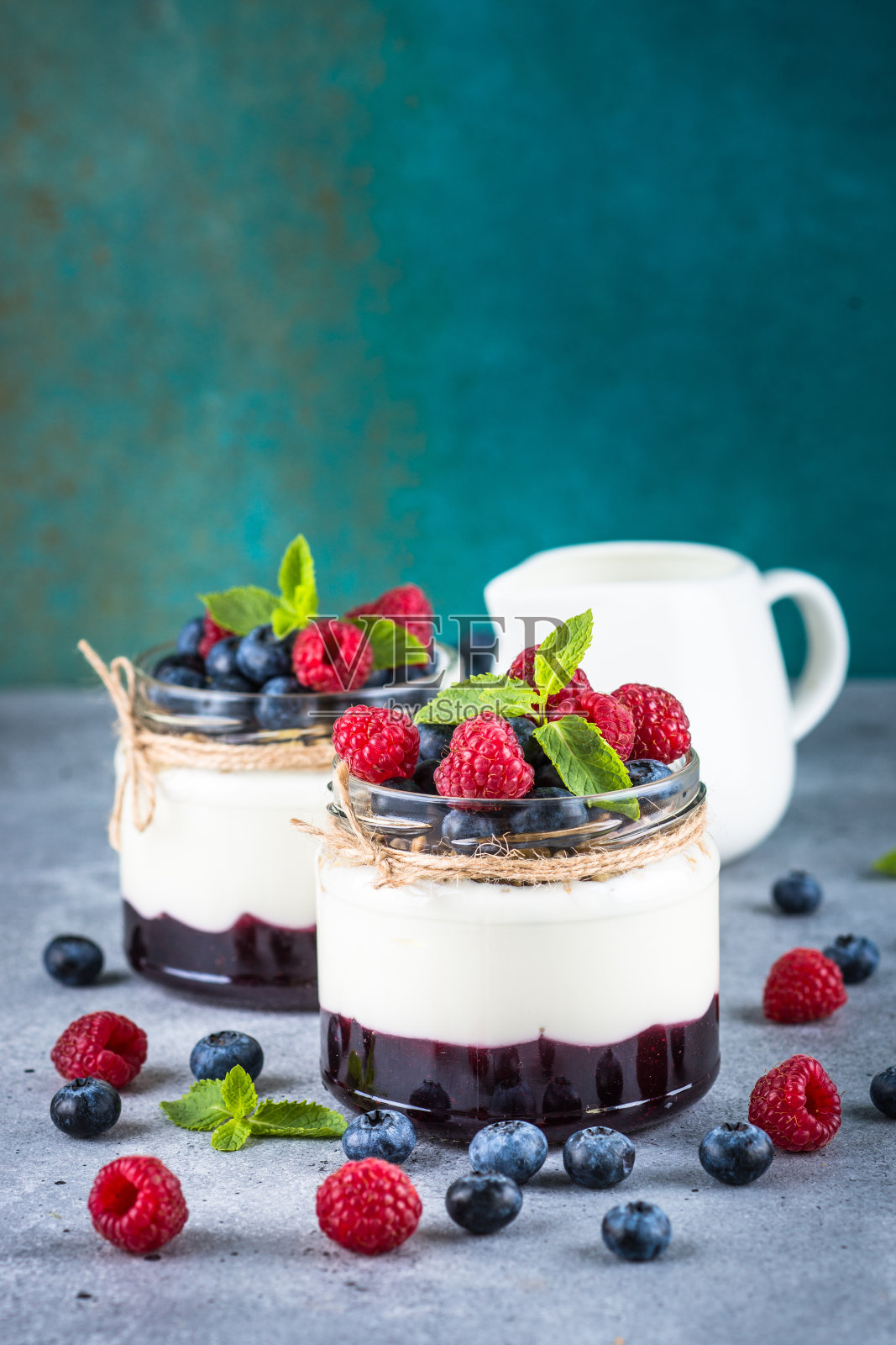 玻璃罐里的奶油和新鲜浆果冻糕。照片摄影图片