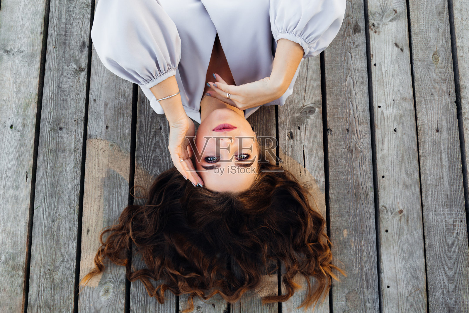 这个女人躺在一个木头表面上,看着相机镜头照片摄影图片
