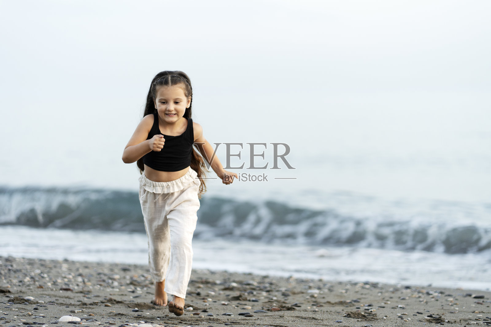 微笑的小女孩在沙滩上奔跑,玩得很开心。旅游,度假,夏季的概念照片摄影图片