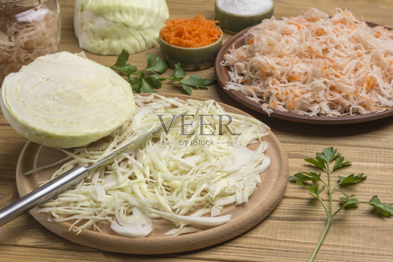 盘子里放酸菜,生白菜切片,菜板上放刀,白菜头半颗。照片摄影图片