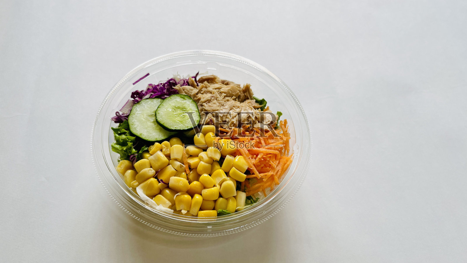 金枪鱼沙拉,用金枪鱼丝,玉米,黄瓜,红卷心菜,纳帕卷心菜,胡萝卜,大葱和亚洲酱放在碗里,用筷子平放在白色的背景上照片摄影图片