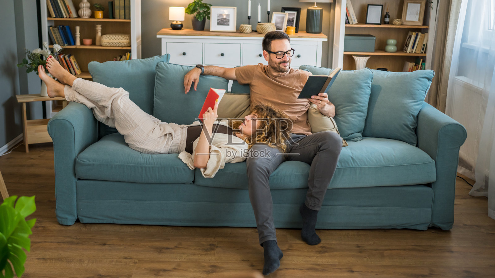 一男一女白种成年夫妇在家里沙发床上看书照片摄影图片