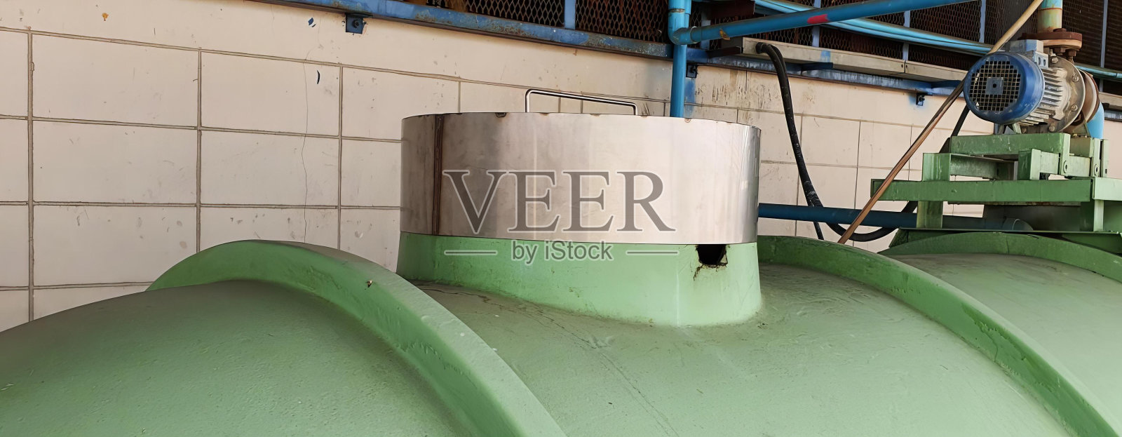 一个大型的绿色管道与金属管道支架的照片,桶式水处理机组与绿色管道和蓝色管道。照片摄影图片