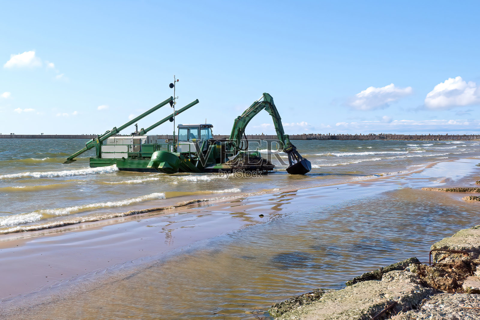 一台漂浮的挖掘机在水中挖泥。照片摄影图片