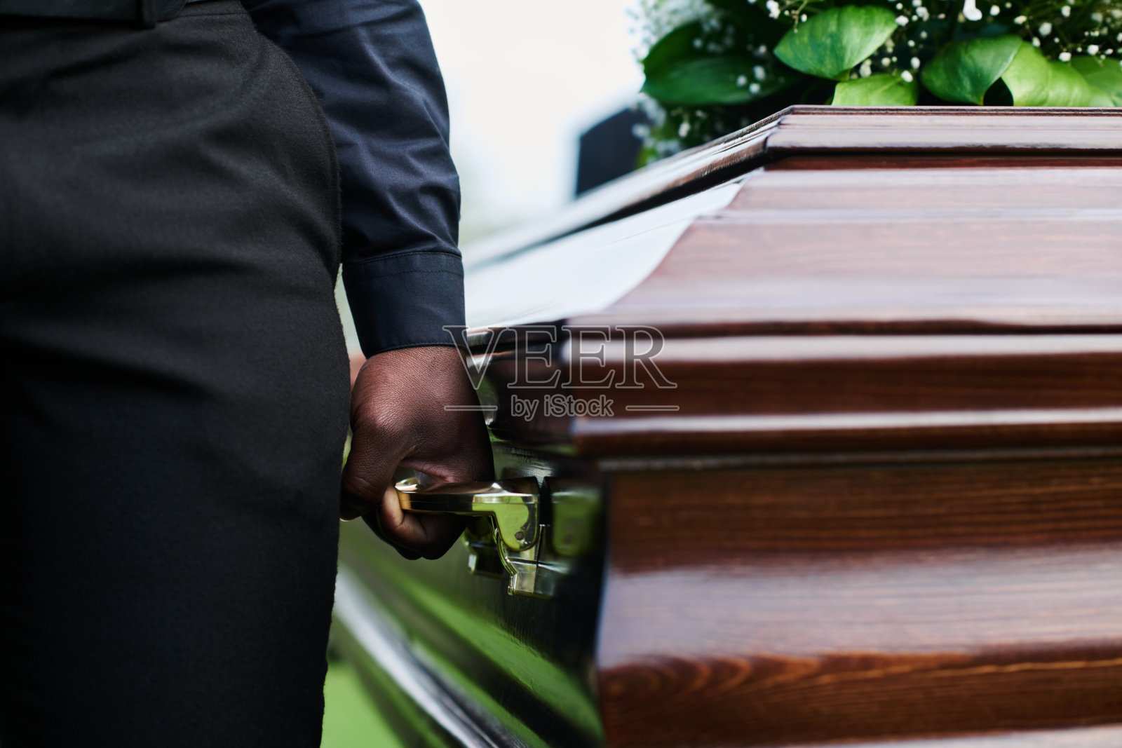 一名男子手持棺木,与其他人一起抬着棺木照片摄影图片