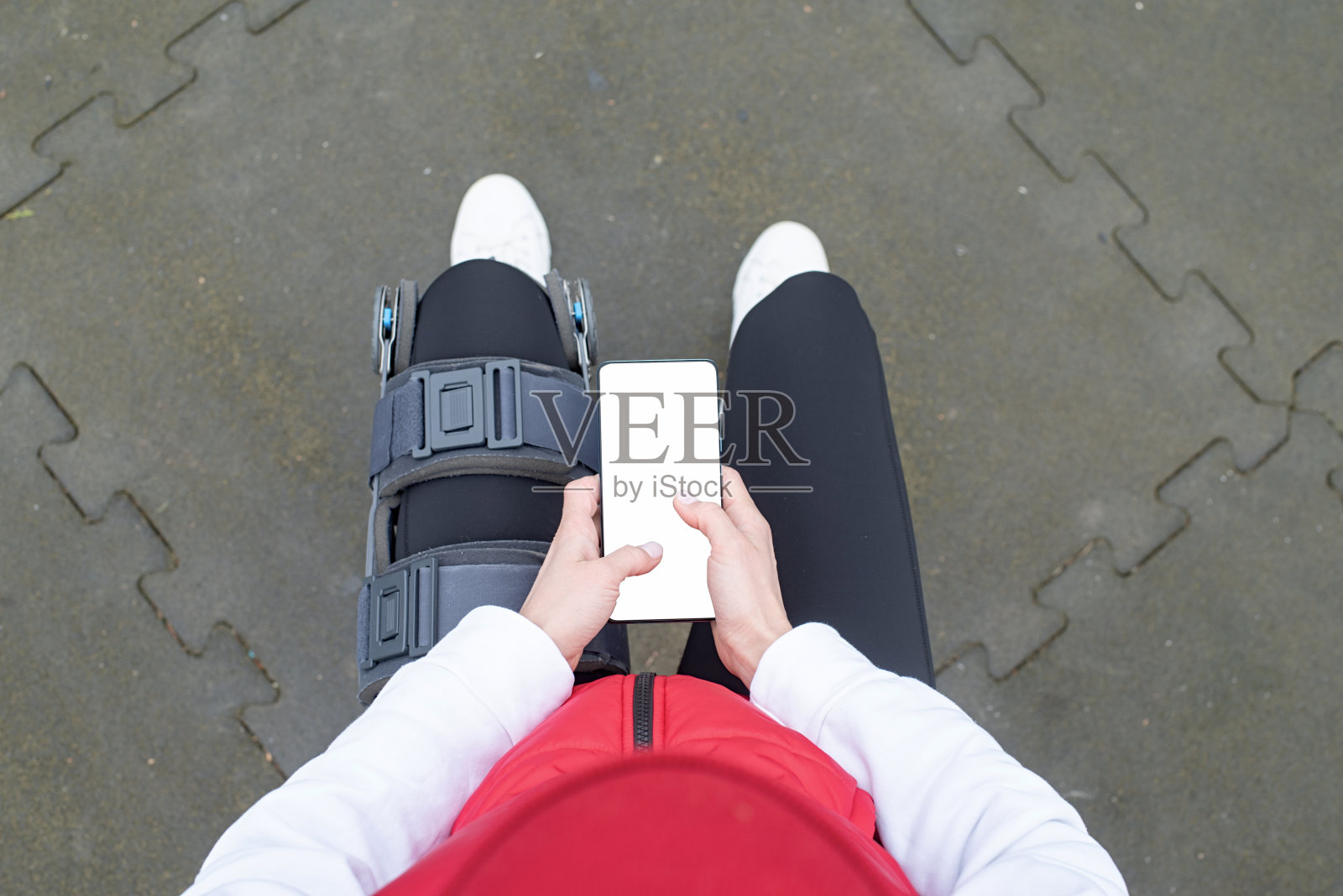 腿部手术后戴着护膝或矫形器的妇女坐在公园里照片摄影图片