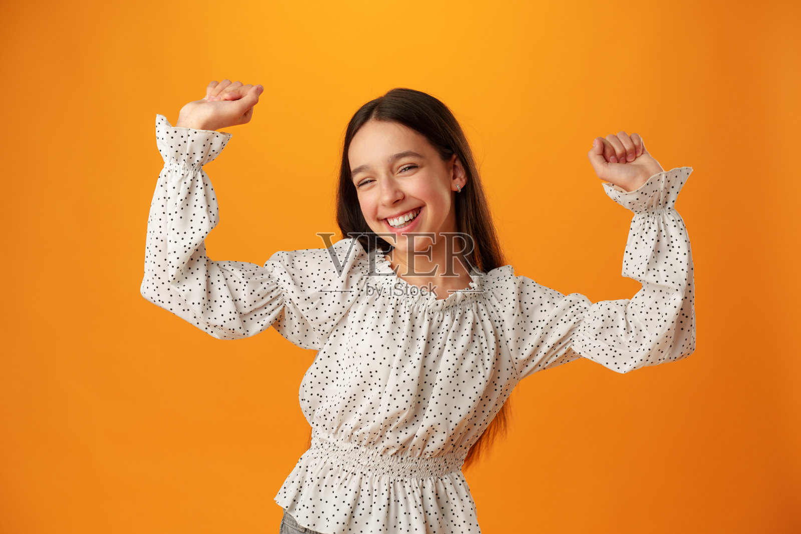 一个快乐快乐的少女在黄色背景上庆祝成功的肖像照片摄影图片