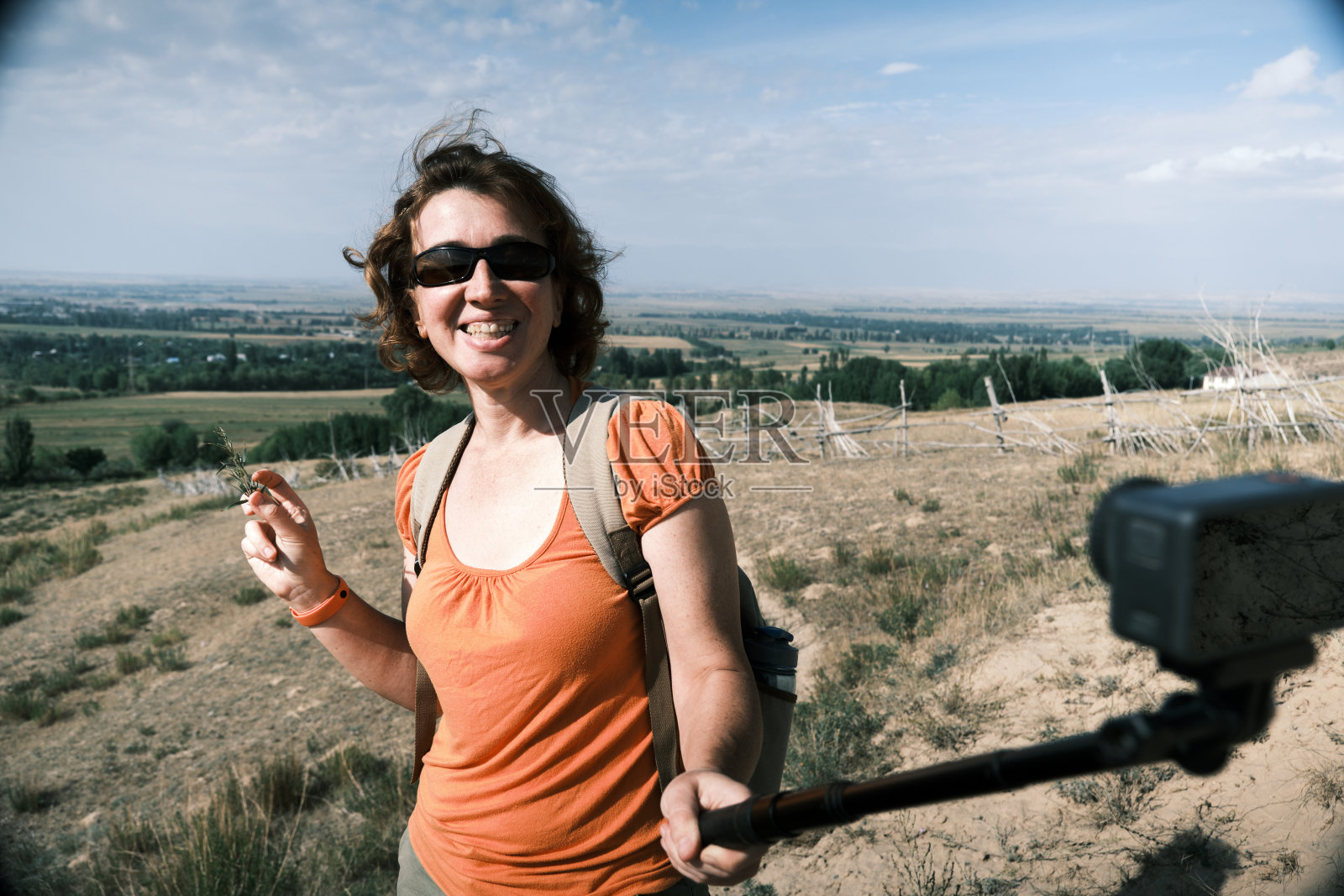 快乐的女游客的肖像是徒步旅行在山麓和流她的徒步旅行照片摄影图片