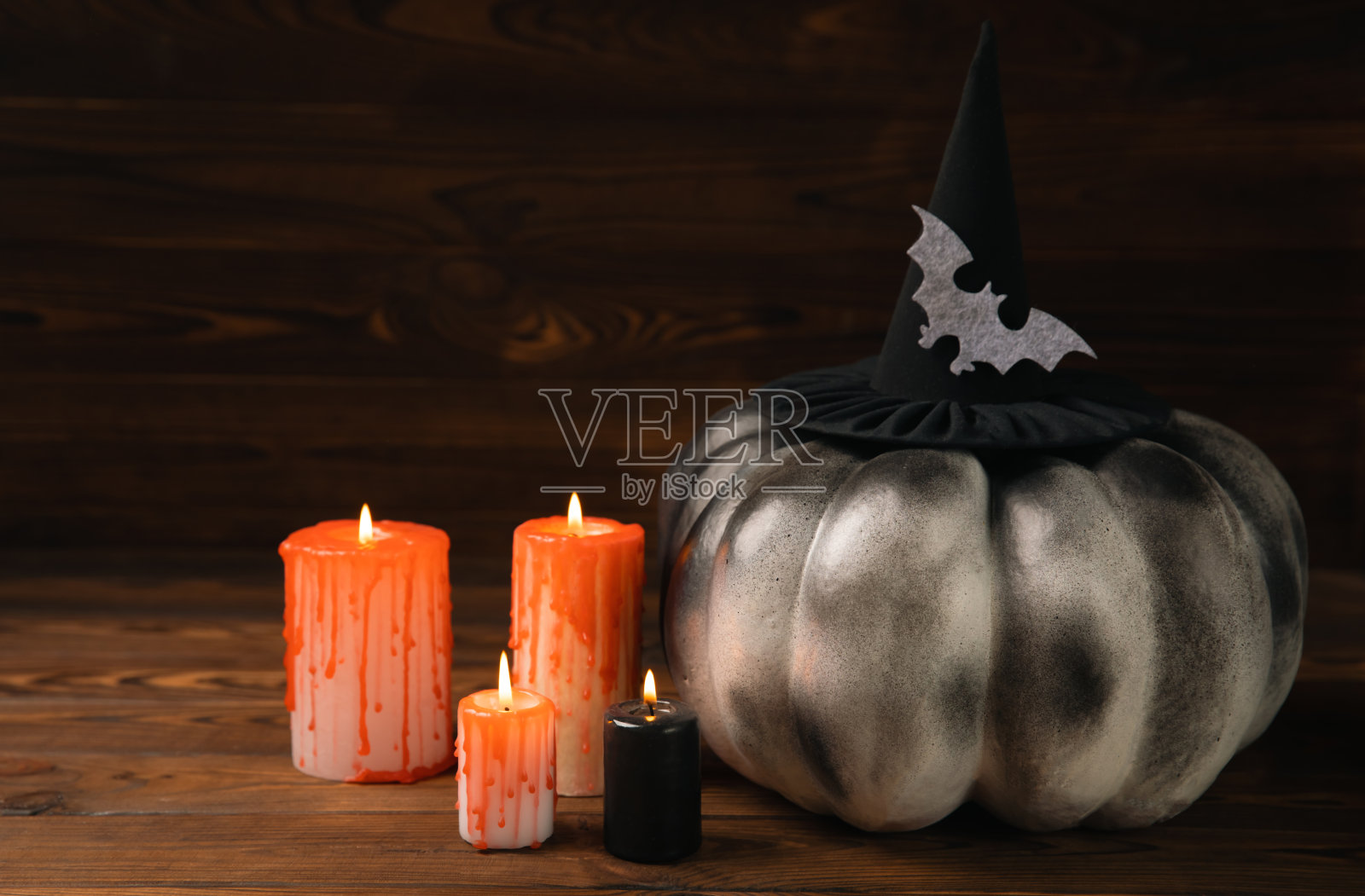 万圣节南瓜上有棕色的木质纹理。暗背景上的构图。可怕的构图与发光的眼睛和嘴。节日的概念。本空间照片摄影图片