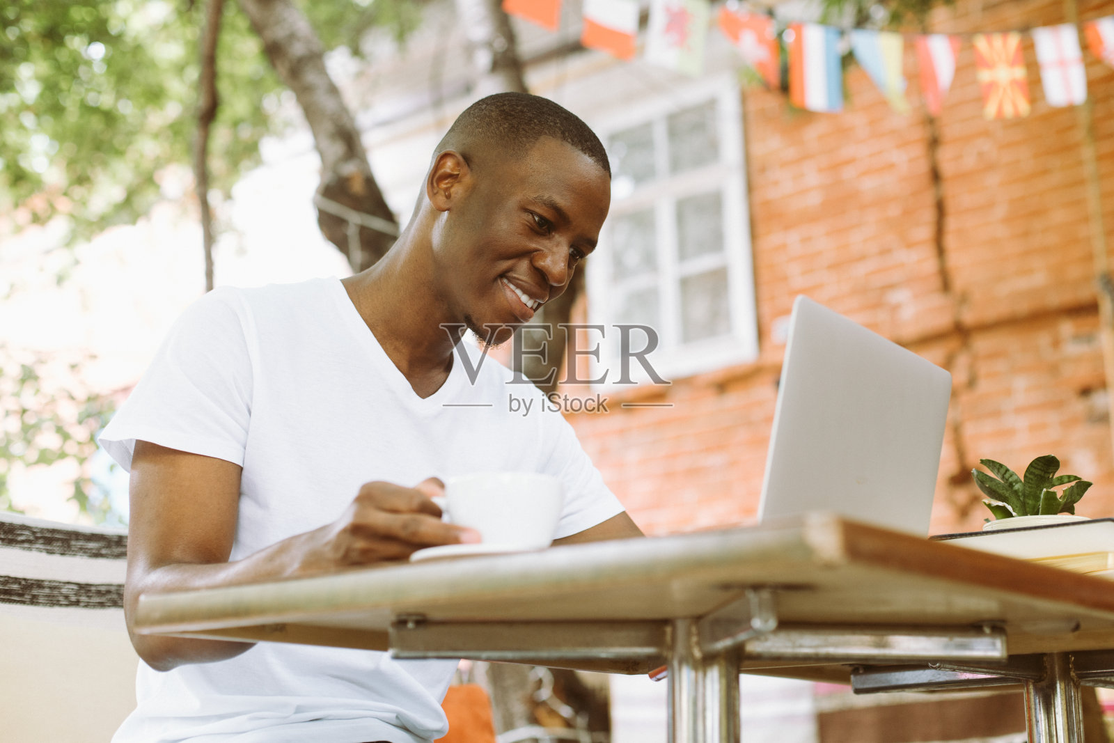 微笑和满意的多种族商人用笔记本电脑在网上工作,在户外喝咖啡。自由远程办公照片摄影图片