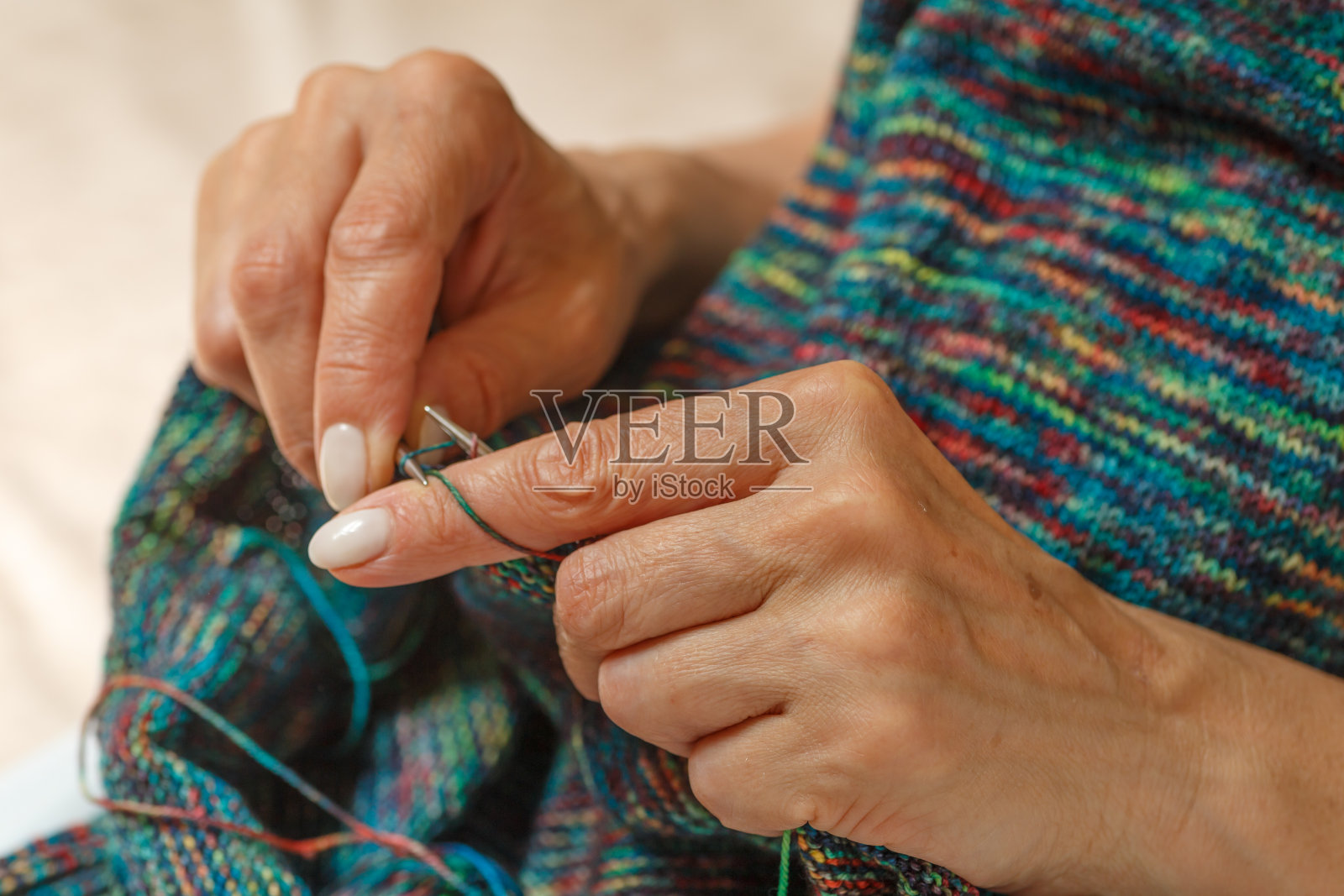 特写的手不认识的妇女编织手工服装与辐条使用羊毛纱线。休闲活动概念。在粗辐条上用纱线编织。照片摄影图片