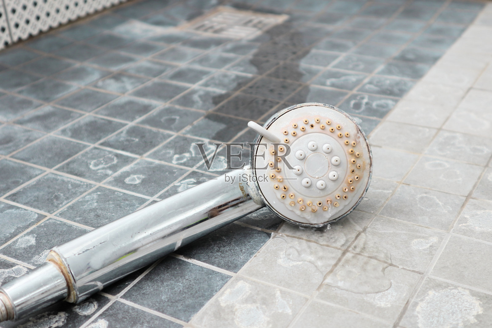 带柠檬皮的银色莲蓬头。淋浴被水垢损坏。照片摄影图片