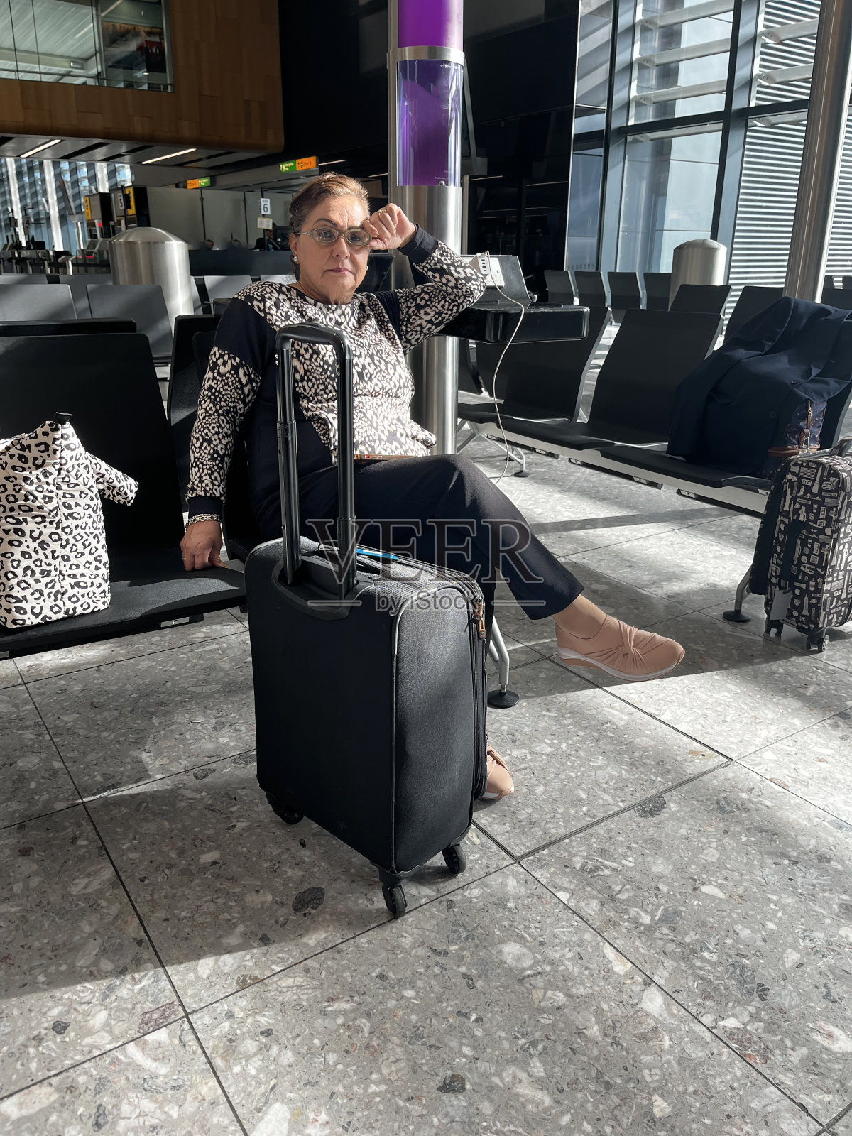 在机场拿着行李的西班牙裔老妇人照片摄影图片