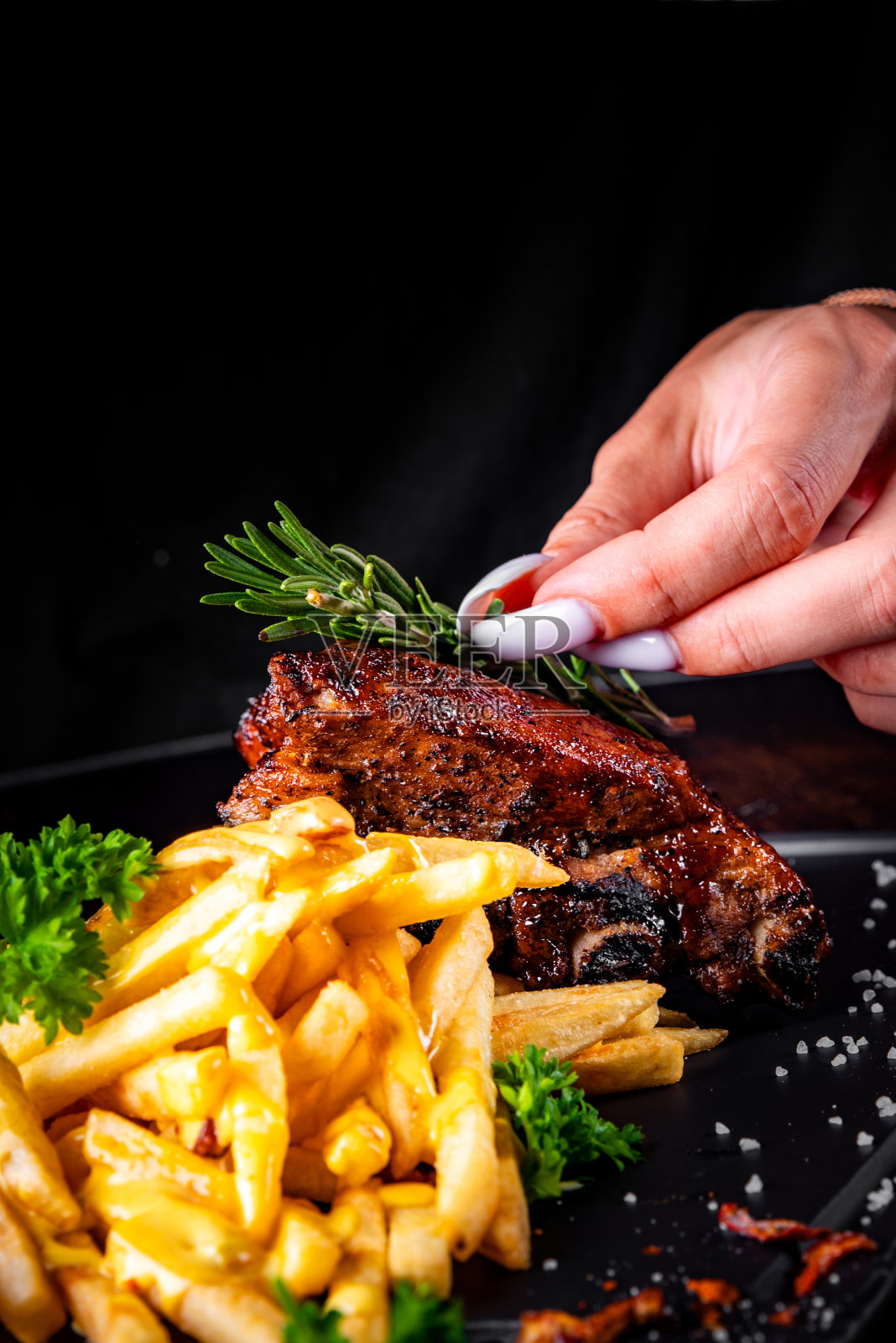 女厨师用薯条和奶酪酱手工装饰猪排照片摄影图片