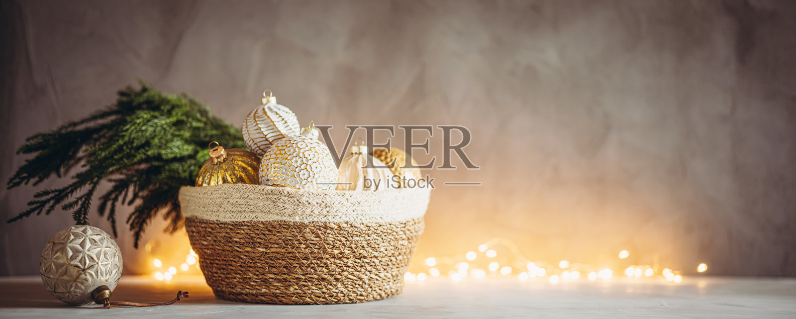 圣诞树的树枝和小玩意在编织篮子与圣诞散景灯的背景照片摄影图片