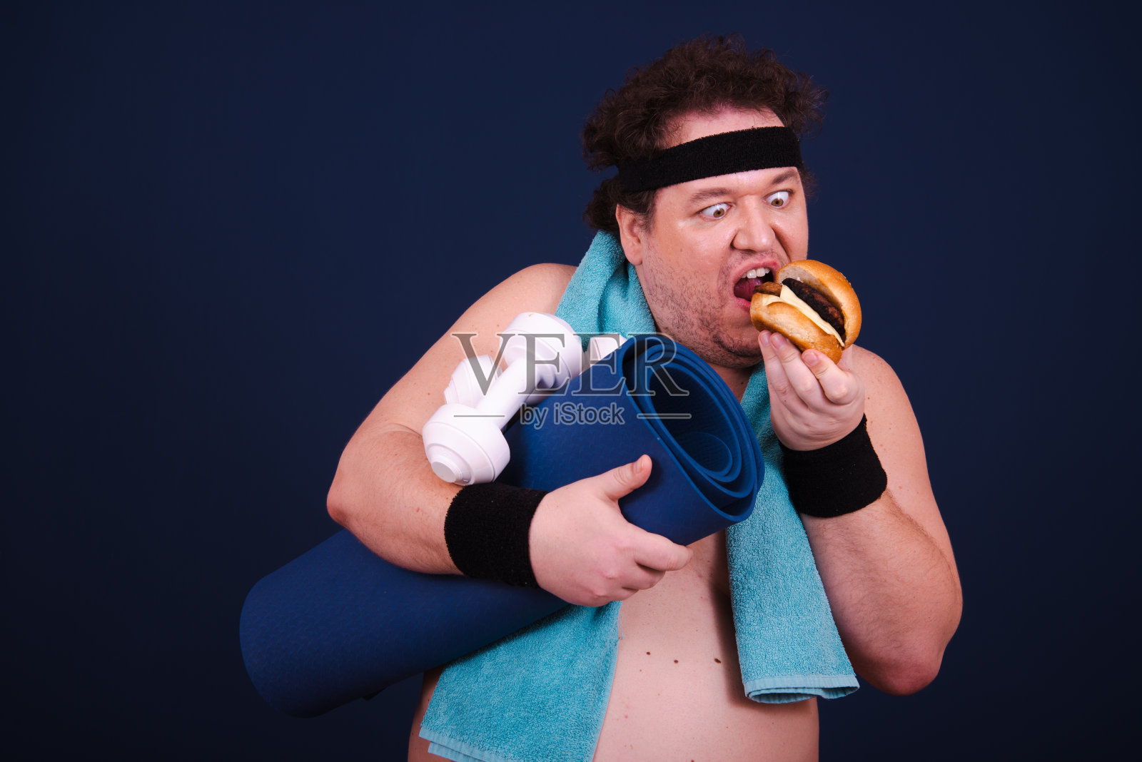 吃汉堡,在健身房健身的滑稽胖子。照片摄影图片