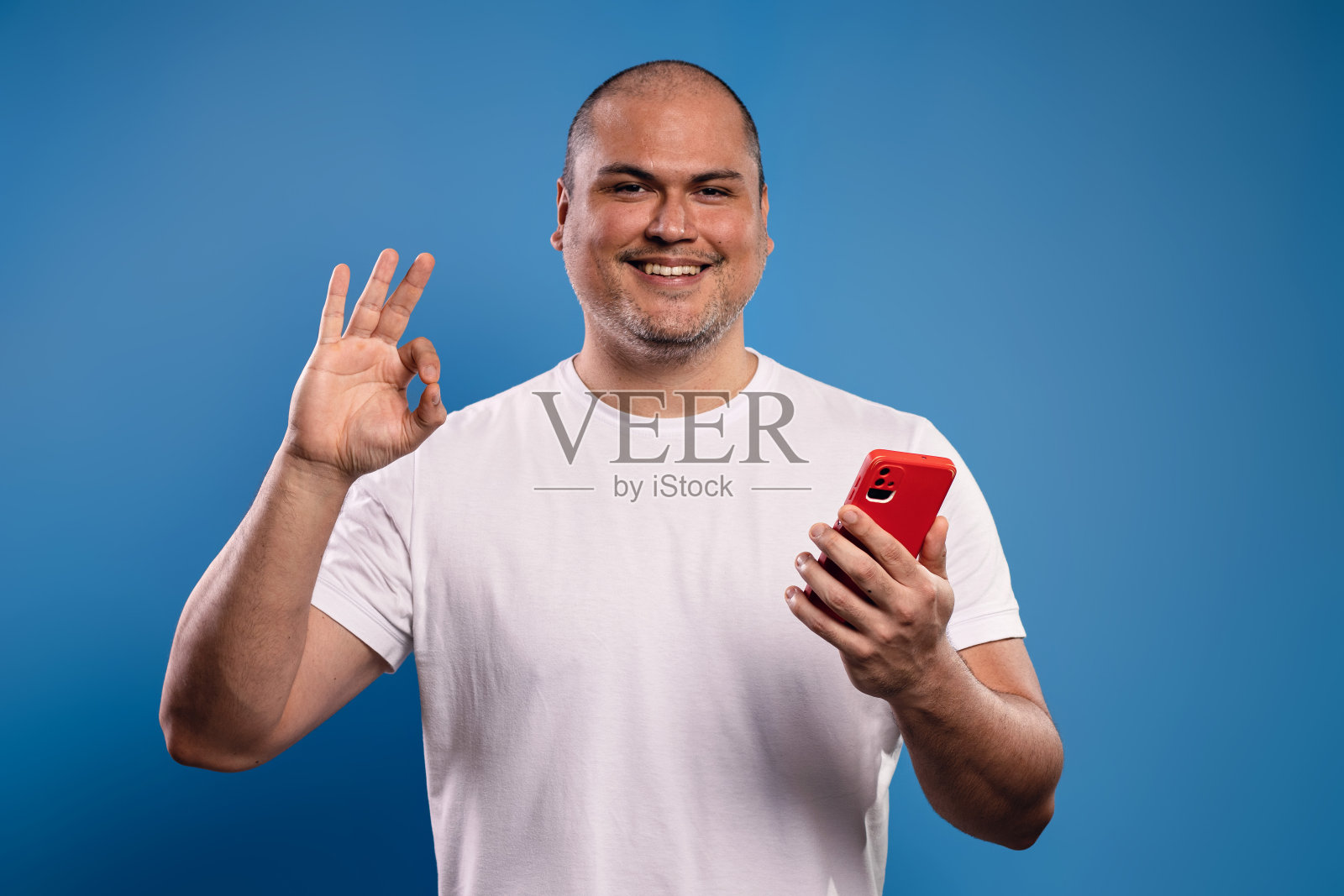 一个拿着手机做OK手势的男人照片摄影图片