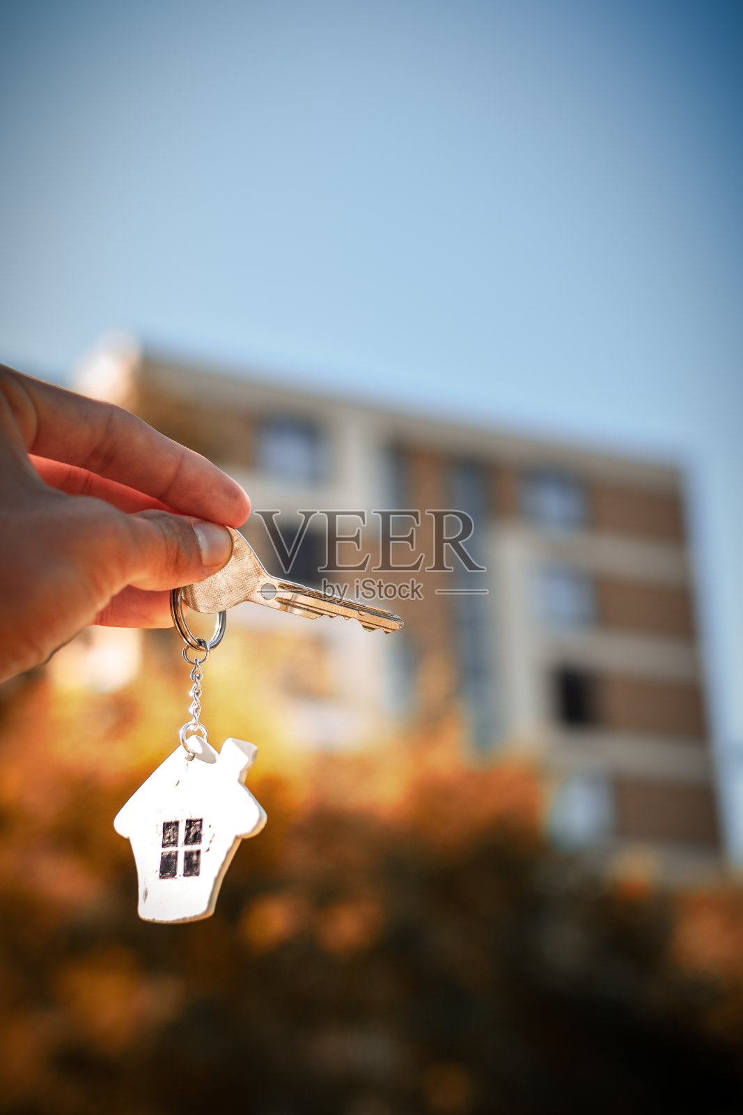 手持钥匙与房屋挂件。照片摄影图片